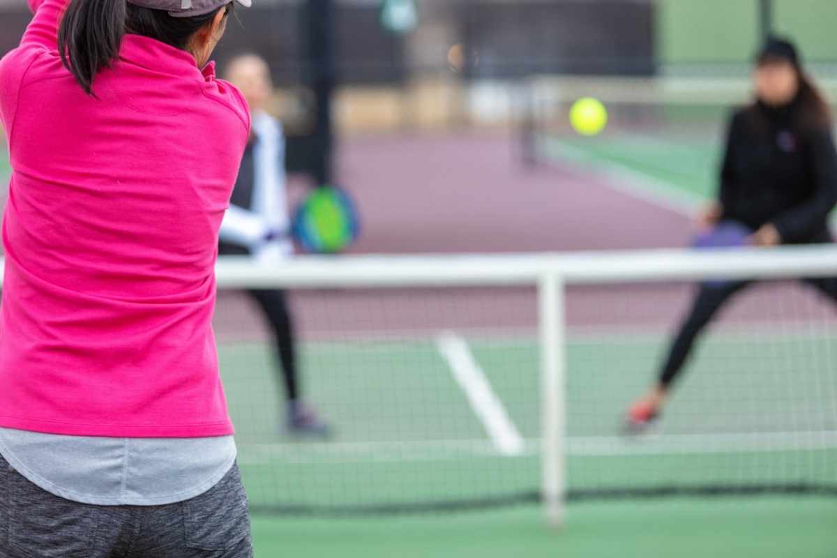 Mixed ethnic group of women playing pickleball outdoors.