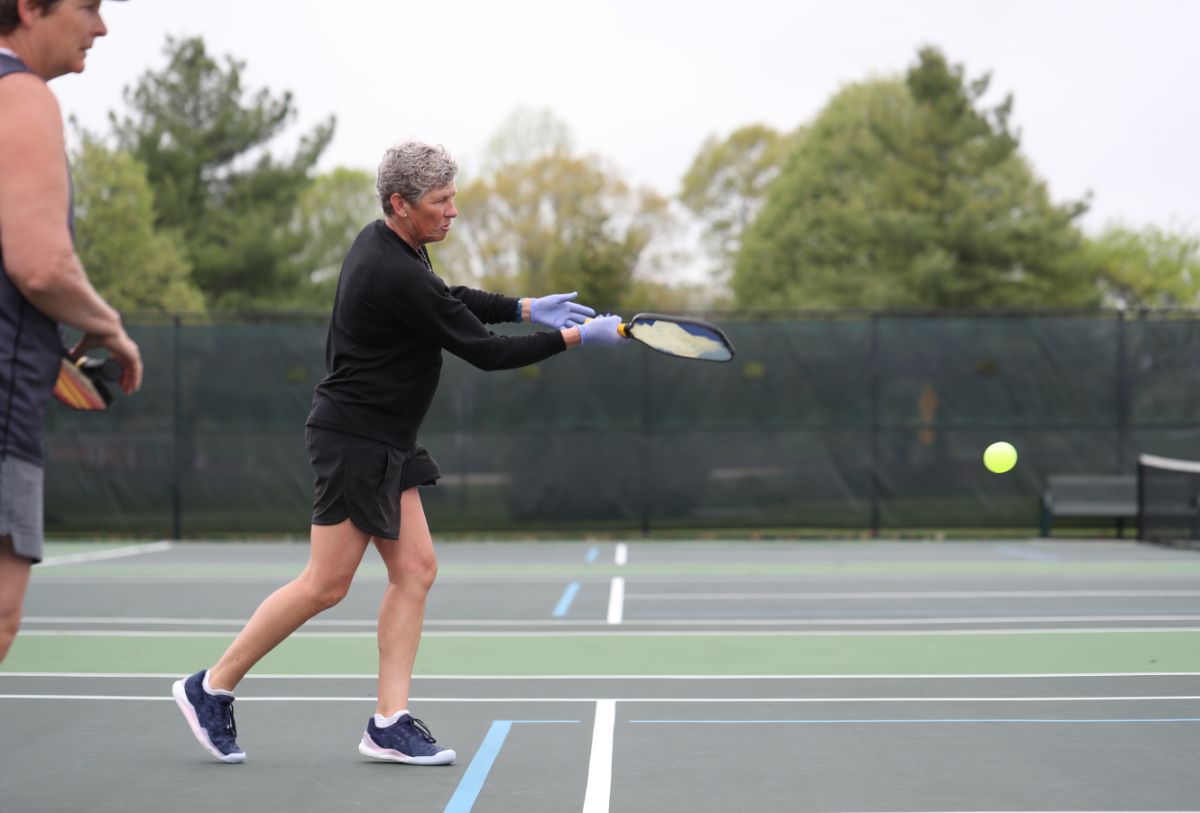 A person missing a shot on a pickleball doubles.