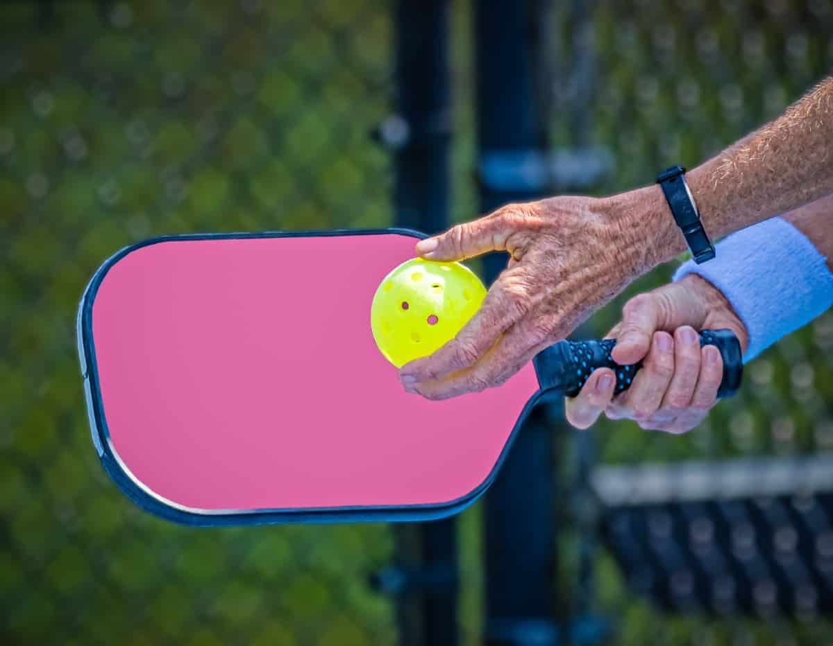 Hands about to serve in a pickleball game.