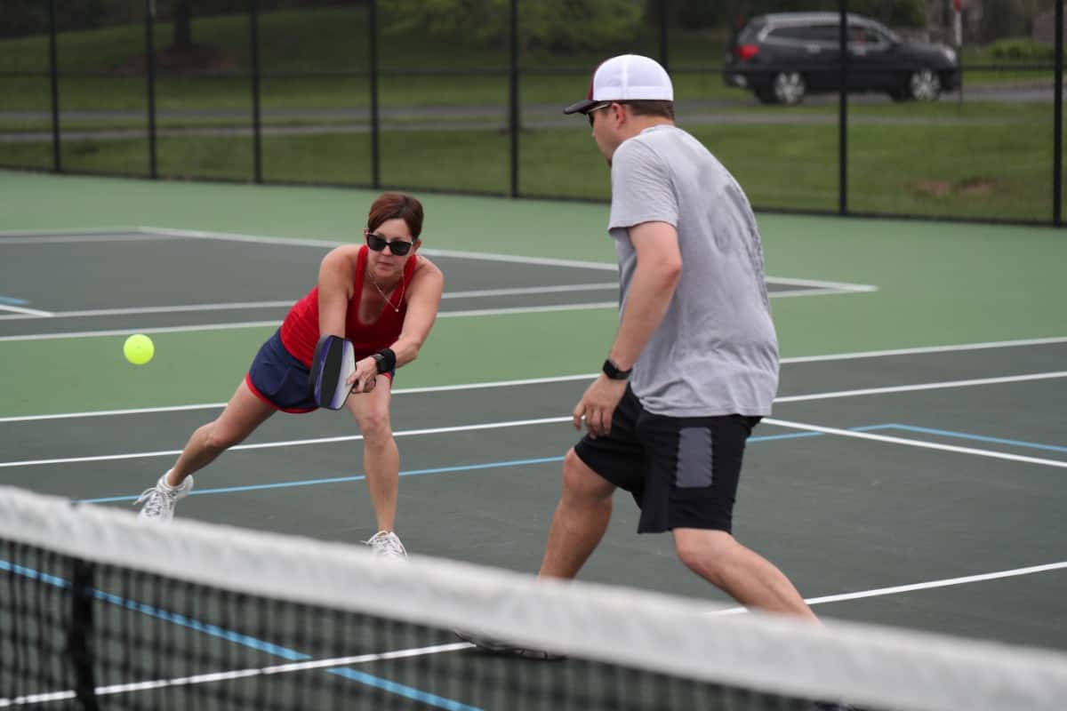 Woman hits a two-handed backhand during a pickleball doubles match.